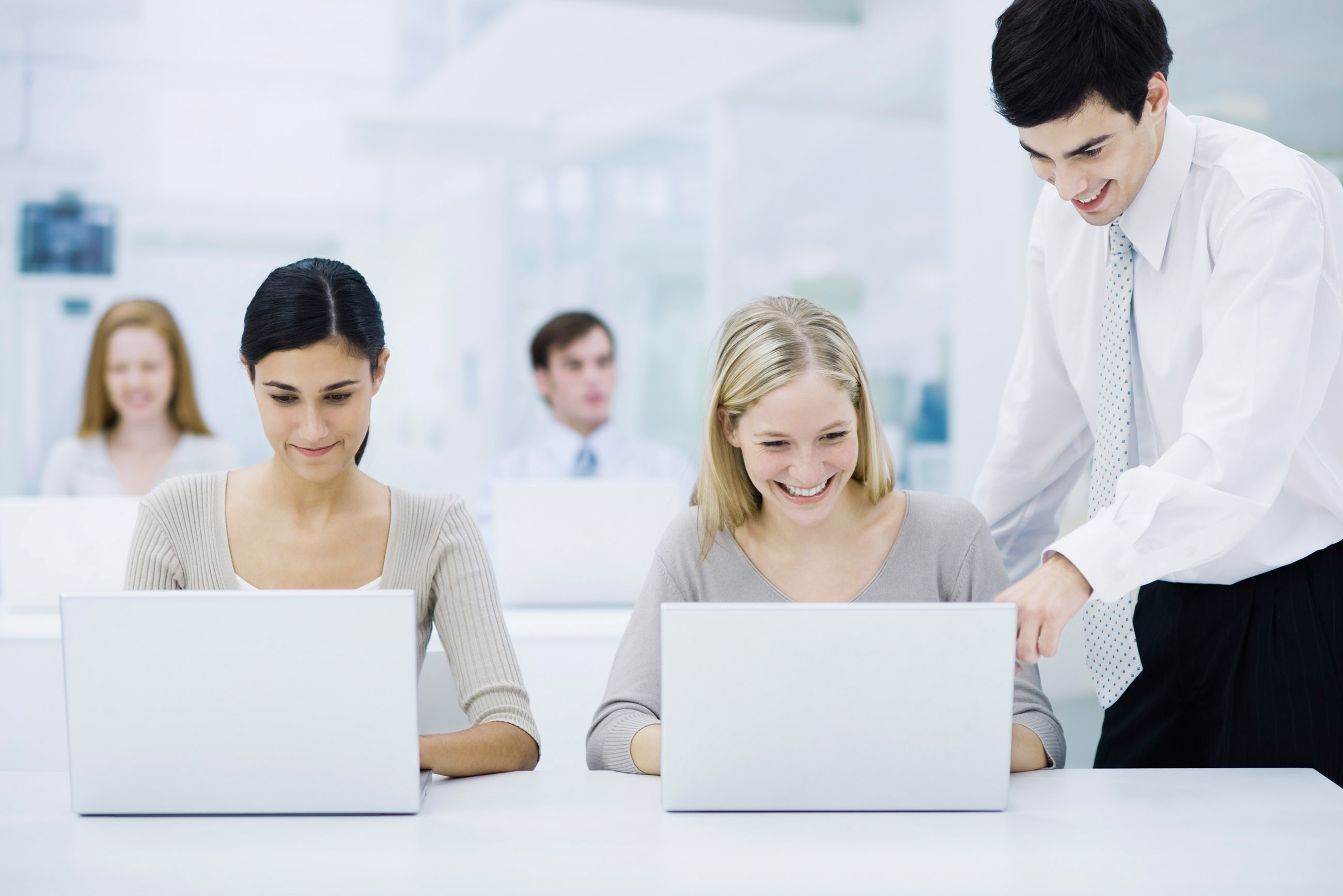 Female Office Worker Using Laptop Computer, Male Supervisor Looking Over Her Shoulder and Pointing